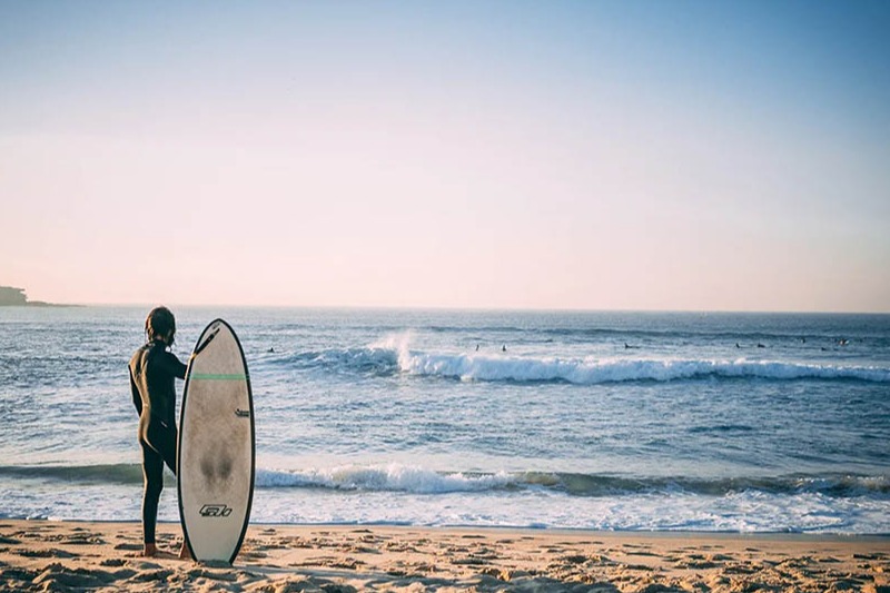 Employee, pictured as surfer on annual leave heading into the surf