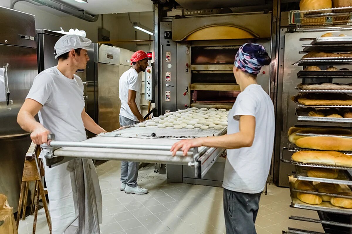 bakers working together to move loaves into oven